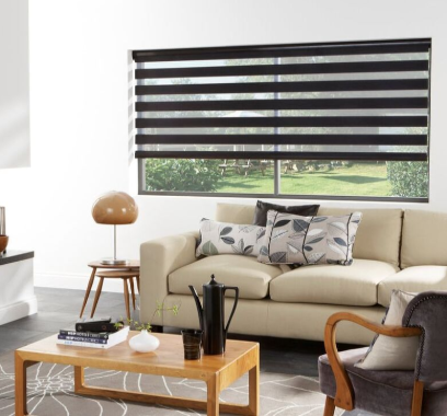 Dark striped roller window shades behind a leather couch in a white room.